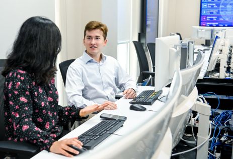 Male and female students talking while sitting at computers in a lab
