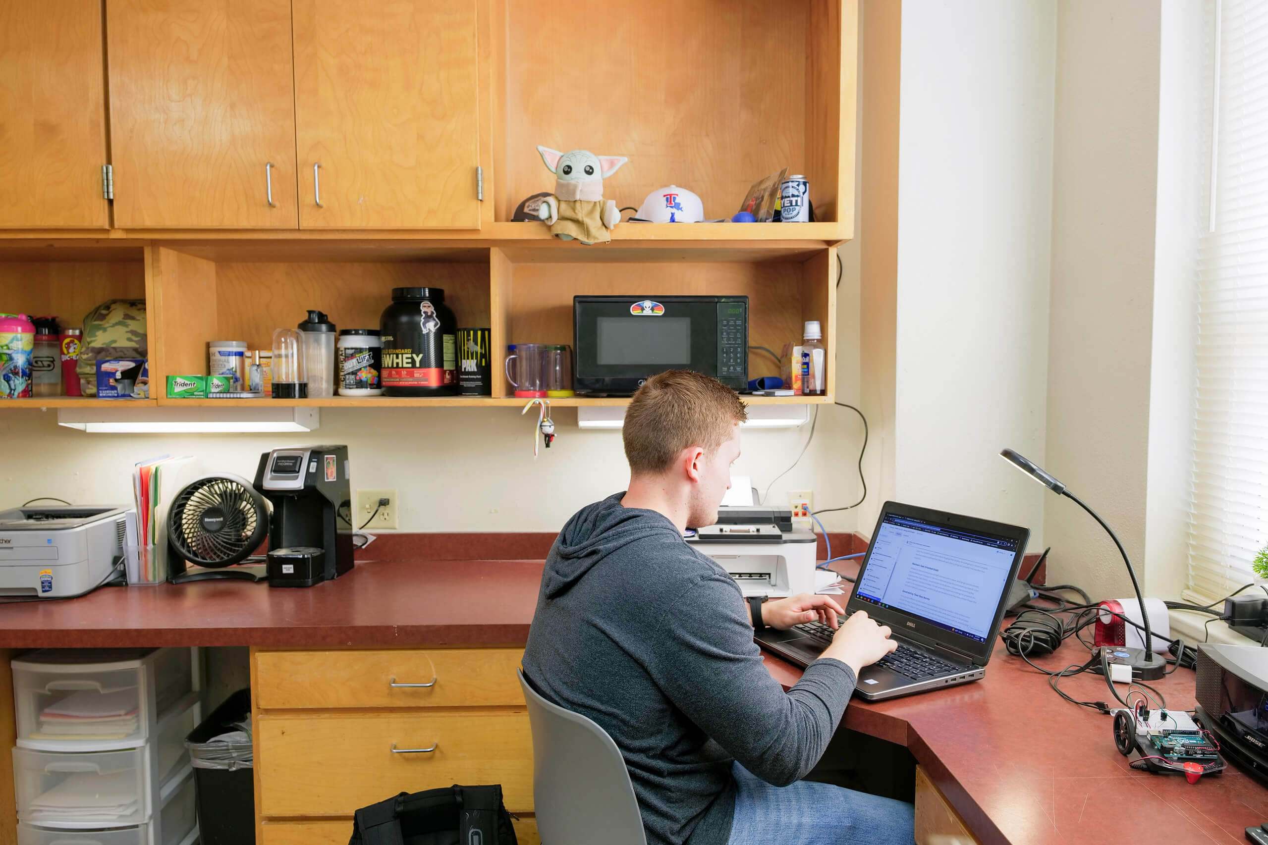 A student works at a desk in a dorm room