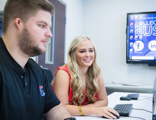 Male and female student sitting at a computer in a lab