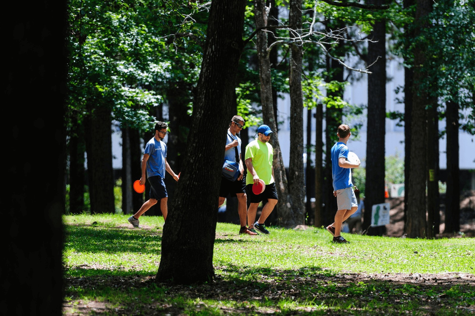 People walk through a park with frisbees in hand to play disc golf