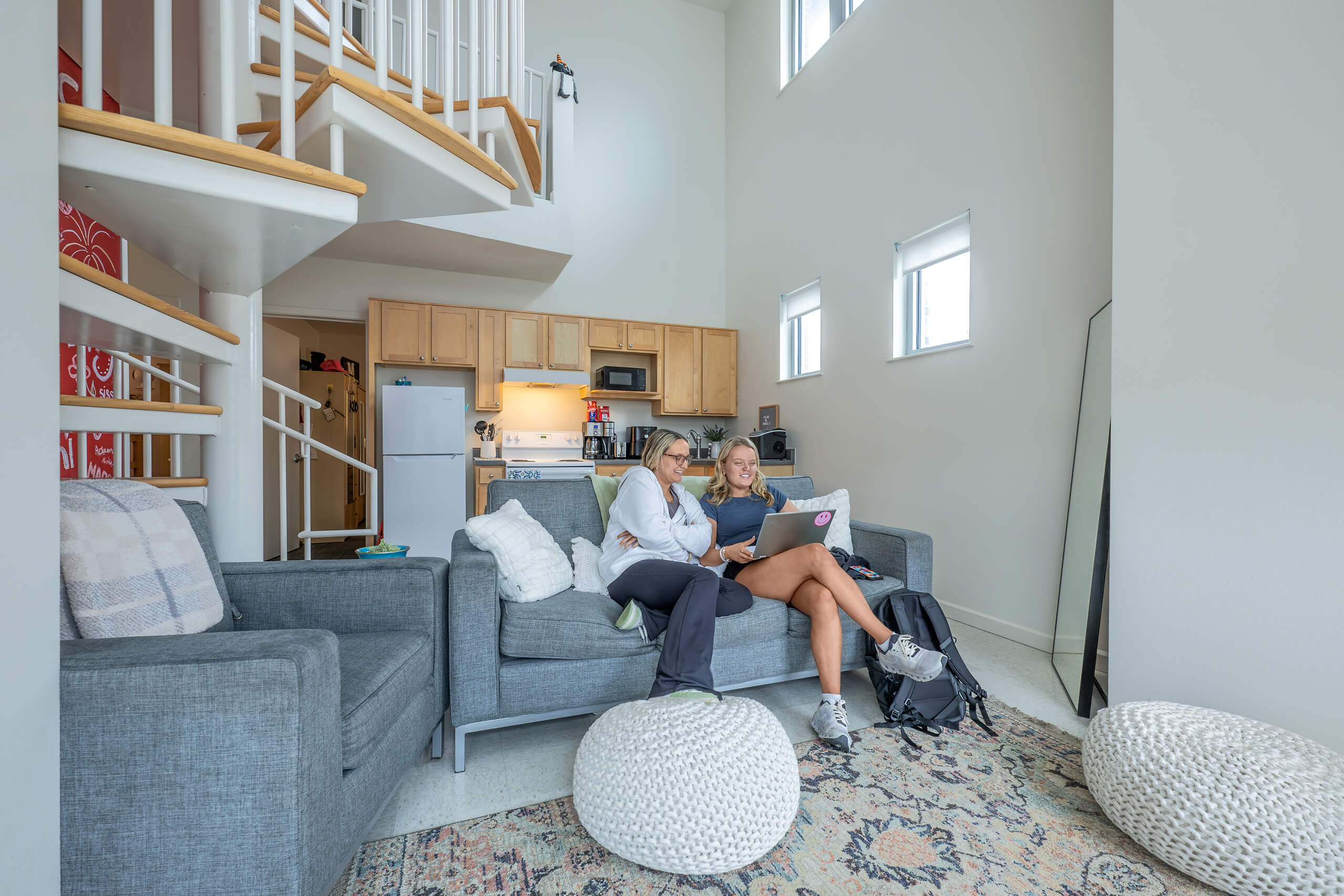 Two people sit on a couch together inside an on-campus apartment living room.