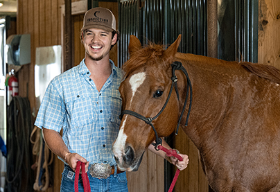 A student walks a horse through the stable.
