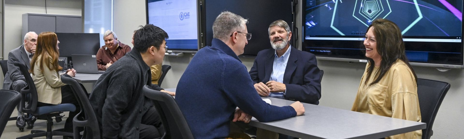 A group of CIS professors are seated around a table chatting