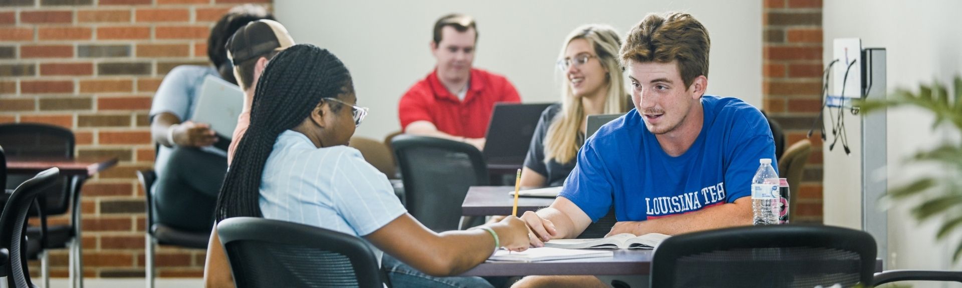 Female and male students talking with each other in the second floor lobby of the College of Business