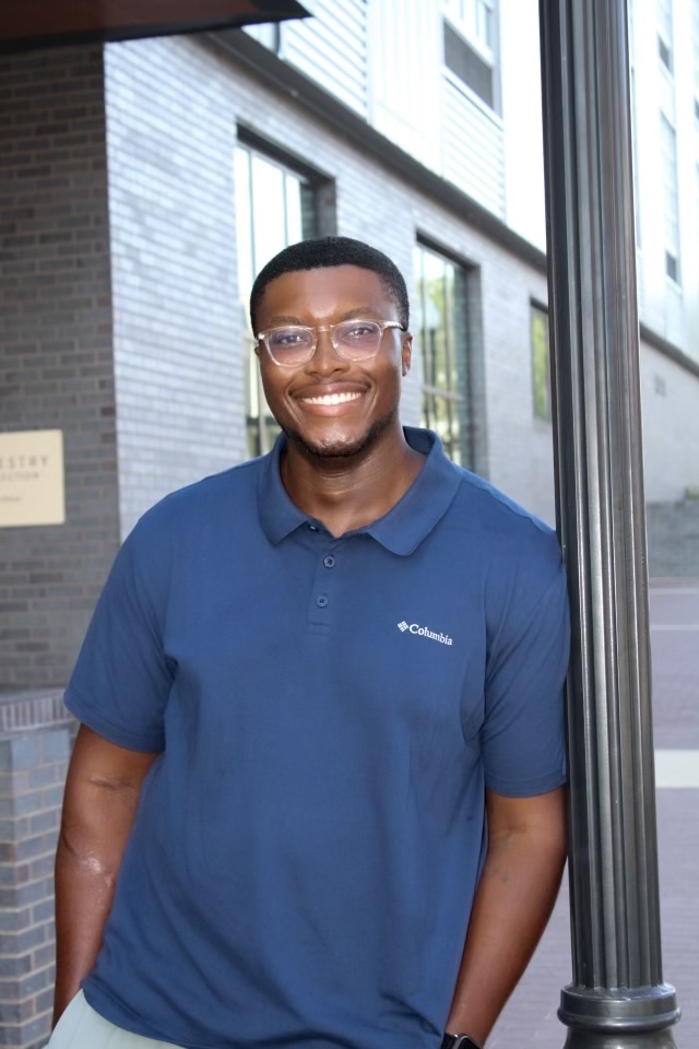Joe Clark wearing a blue shirt in front of a window