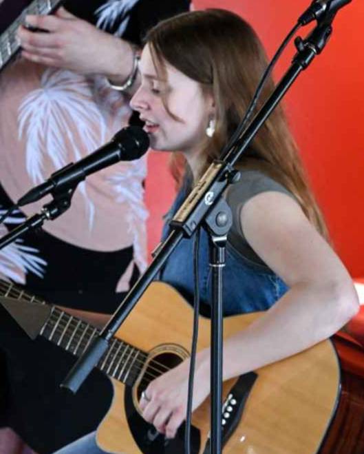 girl playing guitar and singing into microphone