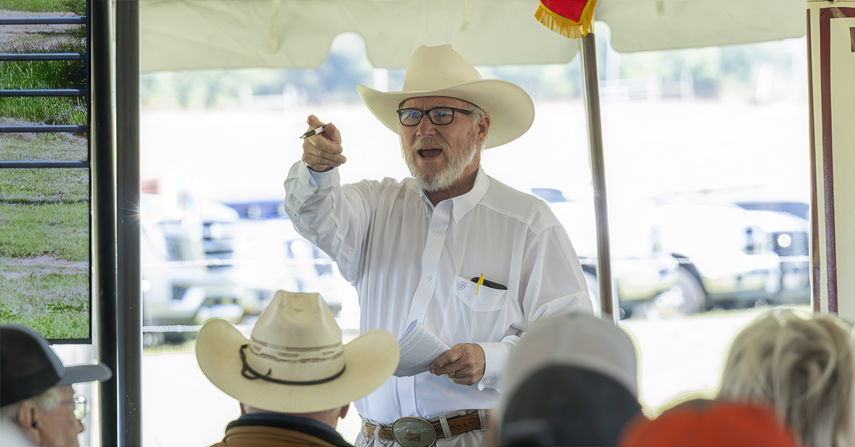 A man in a cowboy hat assists with an outdoor auction