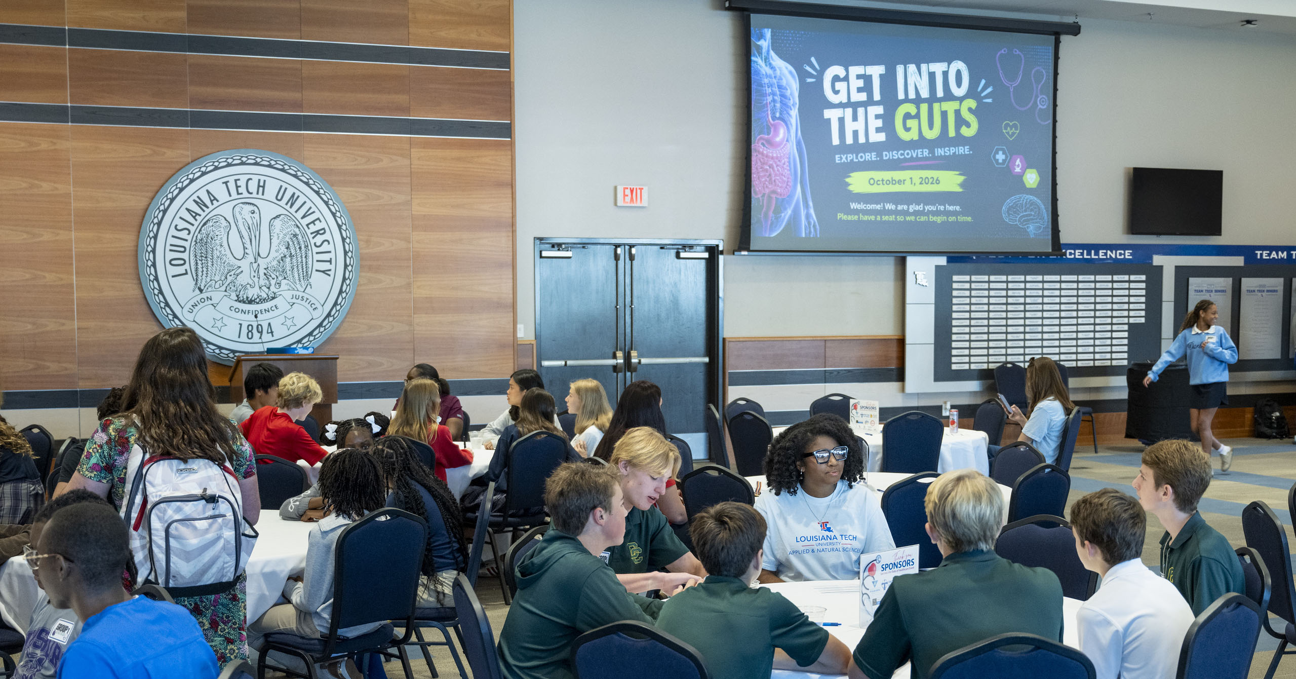 Middle school students sit at tables, learning at the Get Into the Guts of Healthcare event