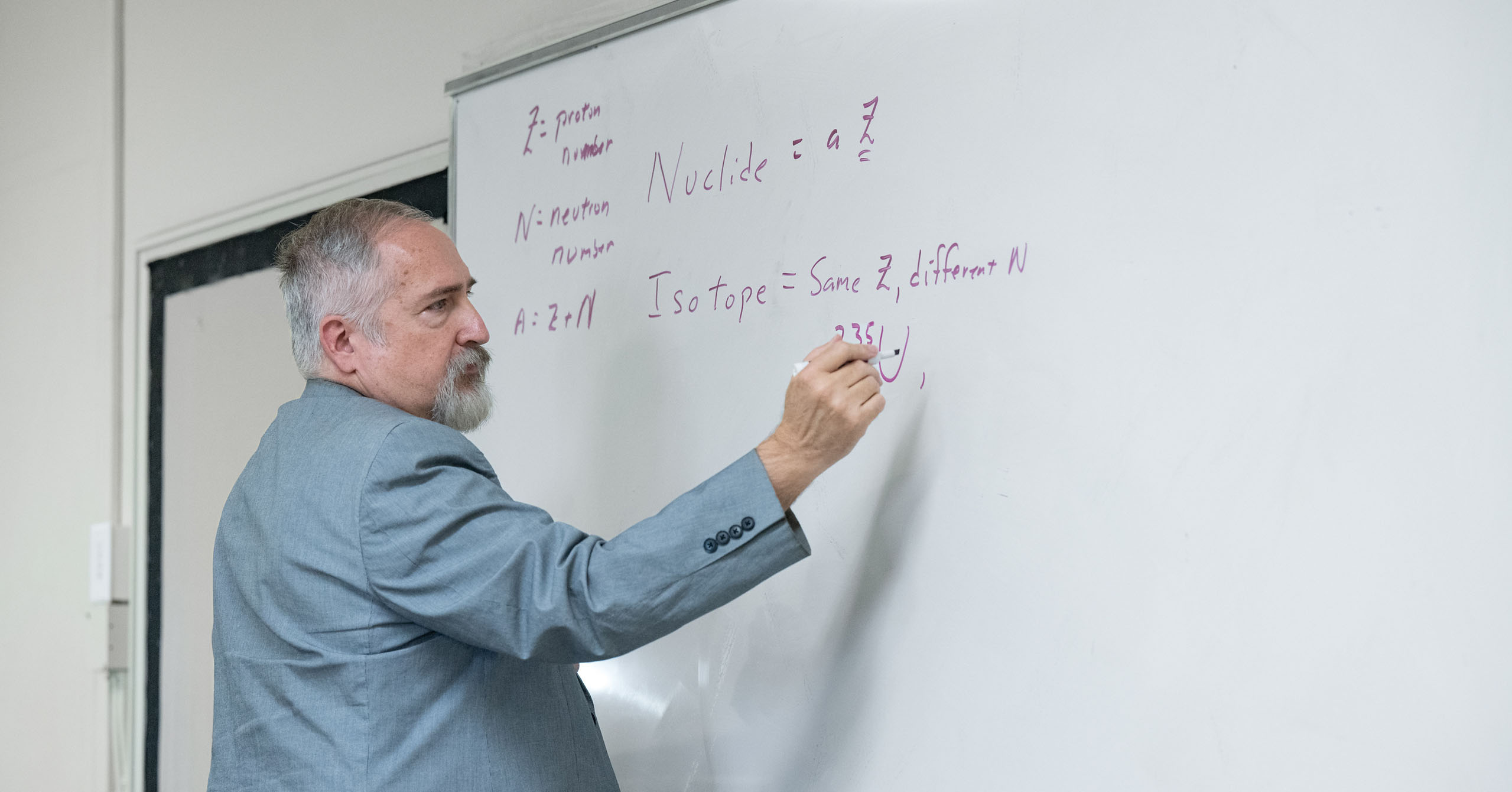 Dr. Lee Sawyer writes equations on a whiteboard