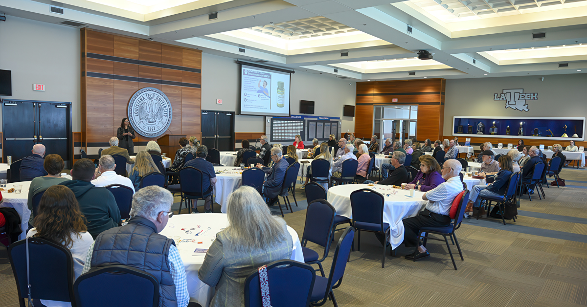 People sit at tables during a presentation