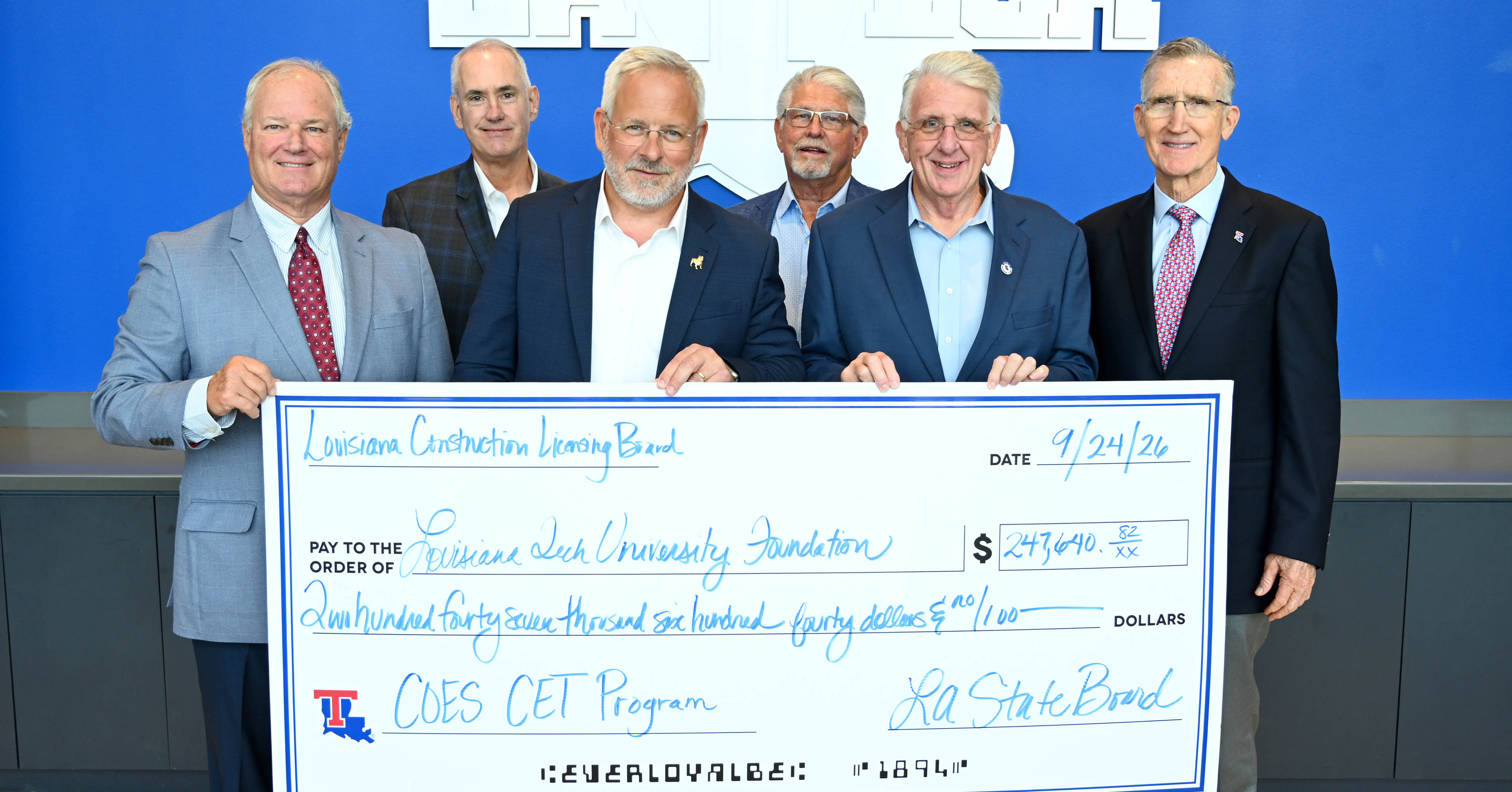 Representatives from the Louisiana Construction Licensing Board and University President Jim Henderson pose with a large check