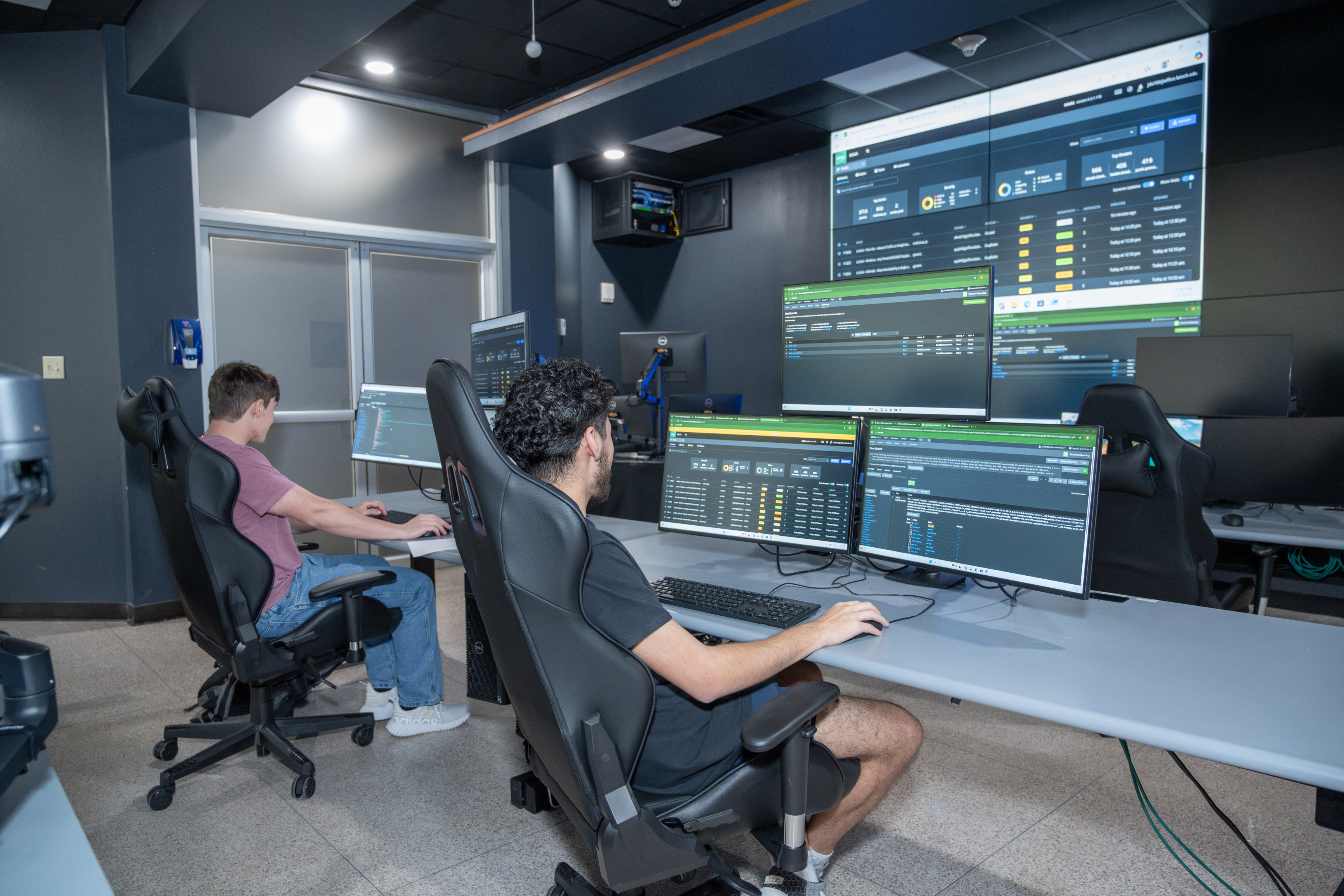 Students inside security operations center sitting on the chair looking at their desktop